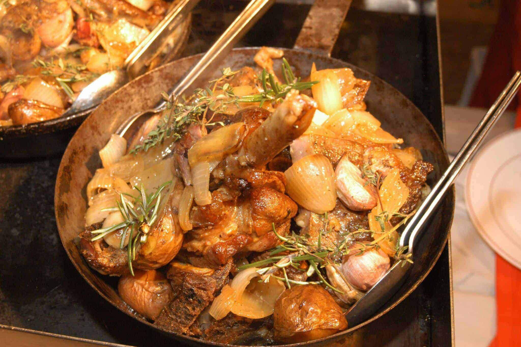 Lungauer Schöpsan mit Zwiebeln und Kräutern in einer Pfanne serviert.