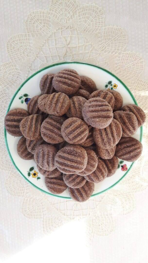 Schokoladige Aronia-Taler auf einem dekorativen Teller, zum Naschen geeignet.