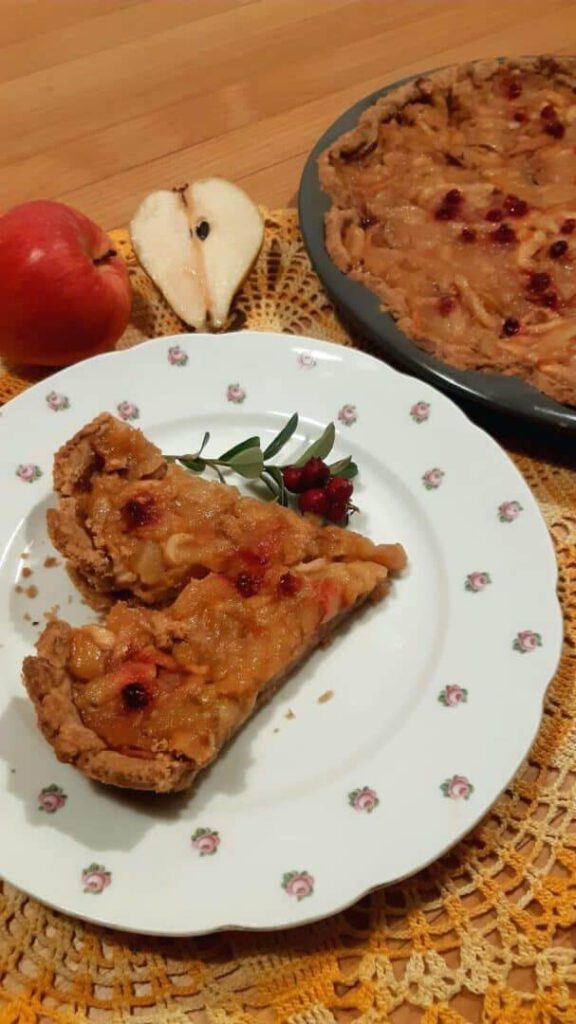 Birnen-Apfel-Tarte auf einem Teller, dekoriert mit einem Apfel und einer halben Birne.